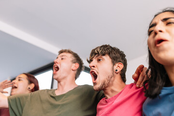 friends screaming with joy watching e-sports on TV after their team's victory. group of young people partying at home.