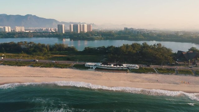 Aerial view of Reserva beach, Marapendi lagoon and car traffic on Lucio Costa avenue. Barra da Tijuca and Recreio, in Rio de Janeiro, Brazil. Sunrise. Sunny day. Drone take. Praia da Reserva.