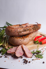 Classic boiled meat pork sausages on chopping board with pepper and basil and cherry tomatoes on wooden background. Snack for kids