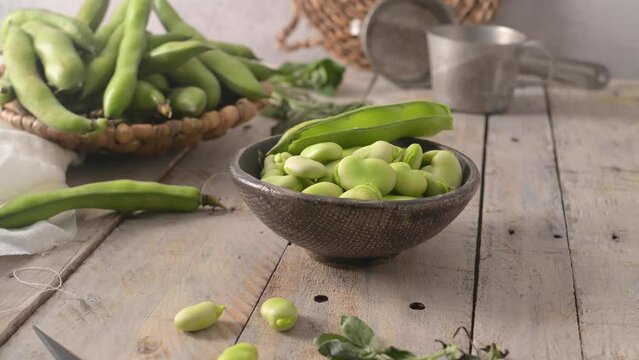 Fresh and raw green broad beans on wooden table.