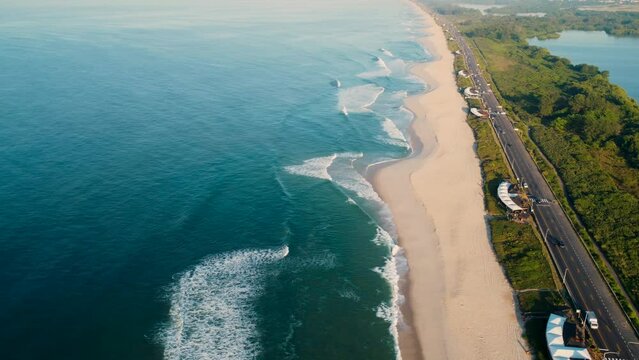 Aerial view of Reserva beach, Marapendi lagoon and car traffic on Lucio Costa avenue. Barra da Tijuca and Recreio, in Rio de Janeiro, Brazil. Sunrise. Sunny day. Drone take. Praia da Reserva.