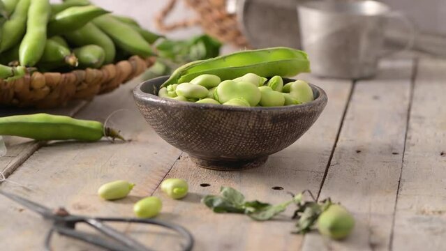 Fresh and raw green broad beans on wooden table.