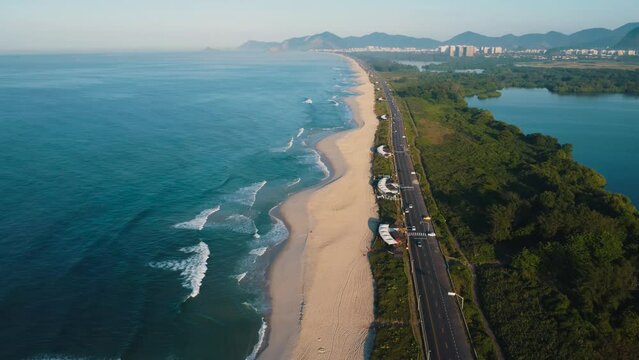 Aerial view of Reserva beach, Marapendi lagoon and car traffic on Lucio Costa avenue. Barra da Tijuca and Recreio, in Rio de Janeiro, Brazil. Sunrise. Sunny day. Drone take. Praia da Reserva.