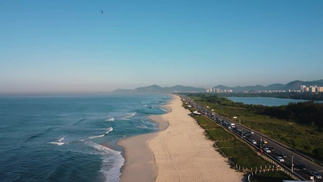 Aerial view of Reserva beach, Marapendi lagoon and car traffic on Lucio Costa avenue. Barra da Tijuca and Recreio, in Rio de Janeiro, Brazil. Sunrise. Sunny day. Drone take. Praia da Reserva.