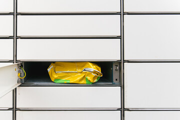 A parcel in yellow packaging lies in an open cell of the post office among other closed cells, rows...