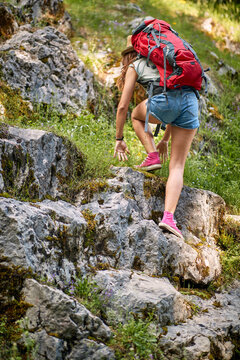 A sexy girl is climbing over the rocks while hiking the mountain. Trip, nature, hiking