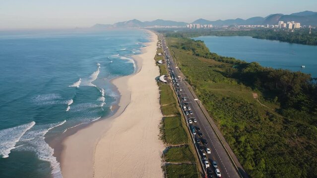 Aerial view of Reserva beach, Marapendi lagoon and car traffic on Lucio Costa avenue. Barra da Tijuca and Recreio, in Rio de Janeiro, Brazil. Sunrise. Sunny day. Drone take. Praia da Reserva.