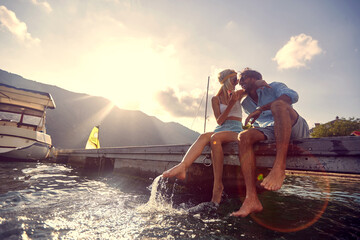 A young couple in love enjoying the water while sitting at the dock on the seaside. Love,...