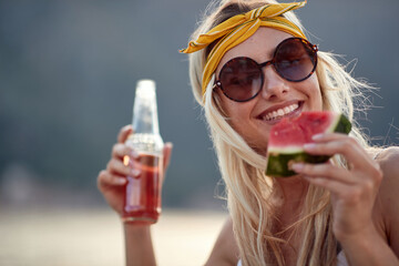 A cute girl is enjoying a drink and juicy watermelon on the seaside. Holiday, sea