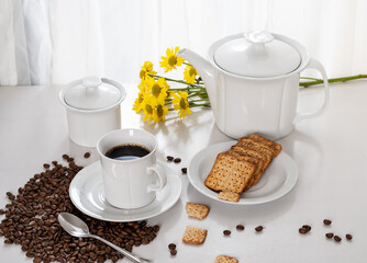 a cup of coffee, wholegrain cookies on a saucer, on a table by the window, light comes through the curtain and illuminates the table, red flower on the table, roasted coffee beans photographed inside 