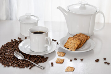 breakfast a cup of coffee and whole grain biscuits on a saucer, on a table near the window, light enters through the curtain and illuminates the table, photographed indoors