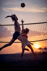 Fototapeta Friends playing beach volleyball.Man and woman on the beach playing volleyball obraz