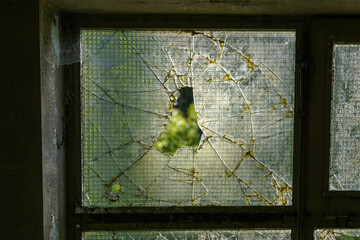 Detail of broken window looking outside of an empty industrial building
