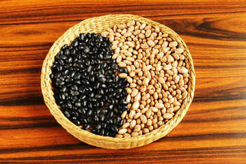 Black and carioca beans in a wicker basket on the rustic table.