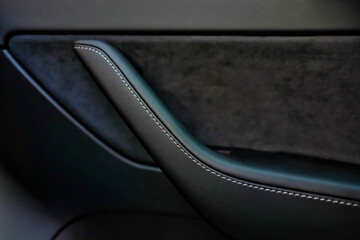 Selective focus of black leather door handle inside car. Design element.