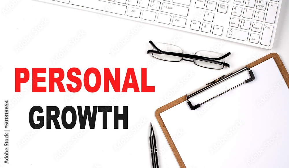 Poster personal growth text written on the white background with keyboard, paper sheet and pen