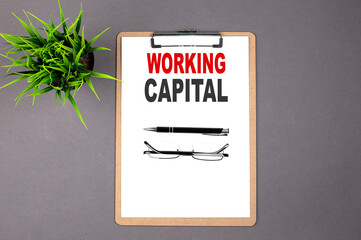 WORKING CAPITAL on the brown clipboard on the grey background. Business concept