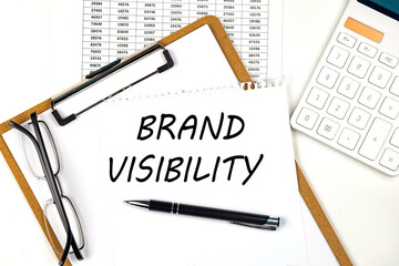 Text BRAND VISIBILITY on the white paper on clipboard with chart and calculator