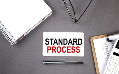 STANDARD PROCESS text written on the card with notebook and clipboard, grey background