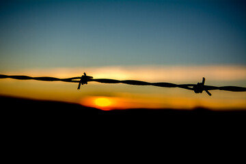 Silhouette of barbed wire at sunrise