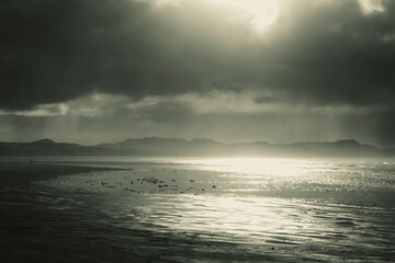 Beautiful sunset above sea or ocean. Vibrant and soft colors, magic light. Small clouds on the sky, reflection of sun in the water and sand on beach. Concept of romantic time on vacation in tropical.