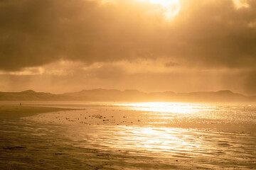 Beautiful sunset above sea or ocean. Vibrant and soft colors, magic light. Small clouds on the sky, reflection of sun in the water and sand on beach. Concept of romantic time on vacation in tropical.