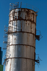 old, rusty storage tank once painted silver on a blue sky