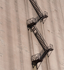 old, precarious emergency staircase on the exterior of a concrete structure - obrazy, fototapety, plakaty
