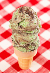 Mint Chocolate Chip Ice Cream Cone on a Red and White Table