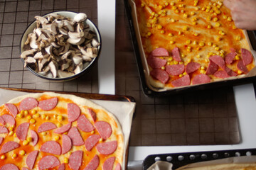 Defocus ingredients for pizza on dough. Red tomato sauce, sausages, sweet corn, mushrooms. Homemade italian pizza. Base of Margarita. Home culinary. Top view. Out of focus