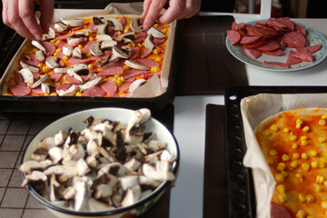 Defocus ingredients for pizza on dough. Female hand cooking. Red tomato sauce, sausages, sweet corn, mushrooms. Homemade italian pizza. Base of Margarita. Dirty table. Home culinary.  Out of focus