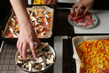 Defocus ingredients for pizza on dough. Female and male hand cooking. Red tomato sauce, sausages, sweet corn, mushrooms. Homemade italian pizza. Base of Margarita. Home culinary.  Out of focus