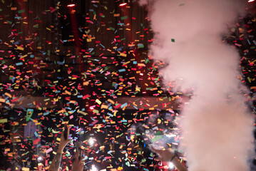 Thousands of confetti shot on air during a night festival. Ideal image for backgrounds. Multicolor are the confetti in the photo. The sky as a background is black.