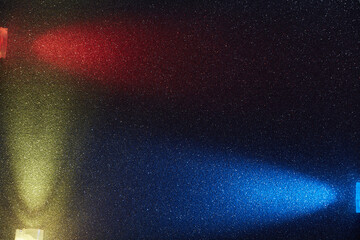 On a dark blue background in fine white grain, rays of red yellow and light blue light