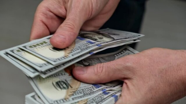 a businessman is counting cash. close-up of male hands counting a stack of hundred-dollar US banknotes. the concept of investment, money exchange, bribes or corruption. selective focus.