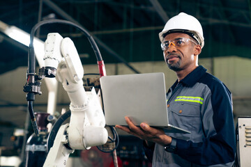 African American factory worker working with adept robotic arm in a workshop . Industry robot...