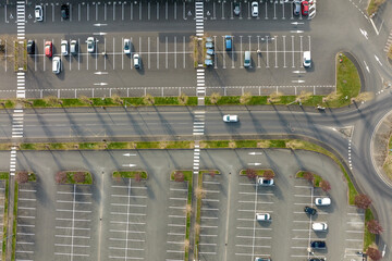Aerial view of many colorful cars parked on parking lot with lines and markings for parking places and directions