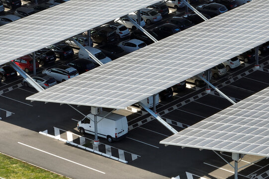 Aerial view of solar panels installed as shade roof over parking lot with parked cars for effective generation of clean electricity. Photovoltaic technology integrated in urban infrastructure