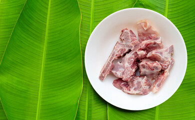 Raw pork bone in white bowl on banana leaves