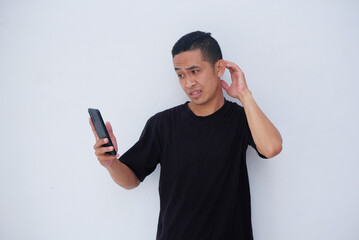 young asian man holding phone with confuse gesture