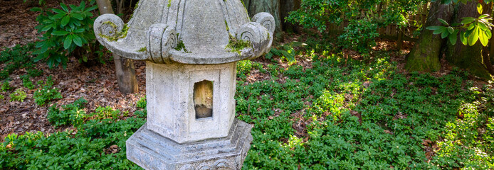 Japanese inspired pagoda lantern in a woodland garden, sunbeams shining in
