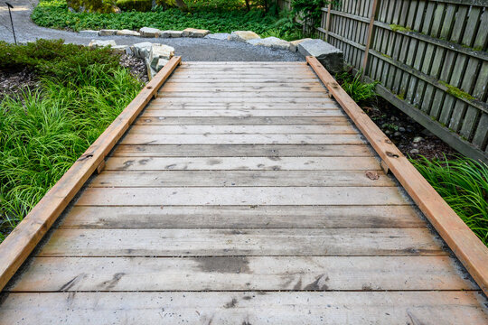 Wooden boardwalk, an invitation to explore a woodland garden
