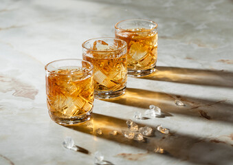 Wiskey whiskey glasses with ice making sun reflection on the surface