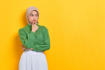 Pensive beautiful Asian woman in green sweater thinking about something and looking away isolated over white background