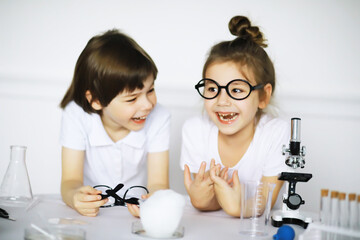 Two cute children at chemistry lesson making experiments on white background