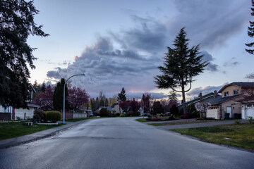 Fototapeta na wymiar Fraser Heights, Surrey, Greater Vancouver, BC, Canada. Street view in the Residential Neighborhood during a colorful spring season. Colorful Sunset Sky.