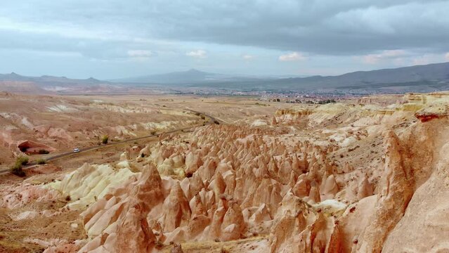 Drone panning view white tour van driving along famous devrent valley desert highway road deserted rocky landscape Monument Valley in Cappadocia. Sightseeing holidays in Turkey
