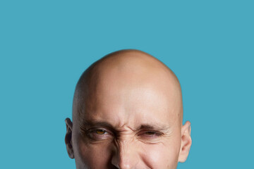 bald young guy close-up on an empty blue background