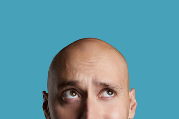 bald young guy close-up on an empty blue background