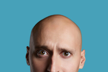 Fototapeta premium bald young guy close-up on an empty blue background